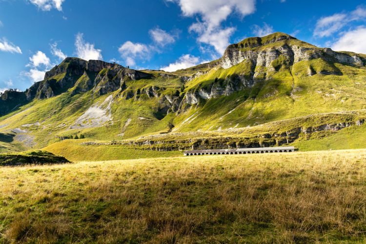 Pastures at the foot of the peaks and, at the bottom, ancient stables for animals