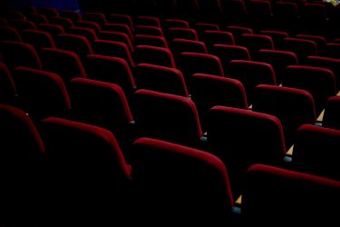 Foto delle sedute di un teatro in velluto rosso.