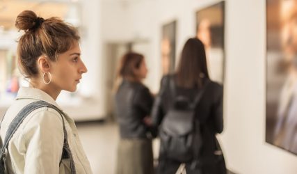 Photo of a girl observing a work of art in a museum
