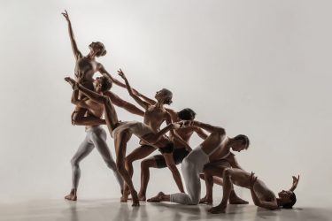 Foto di un gruppo di ballerini contemporanei mentre svolgono una coreografia.