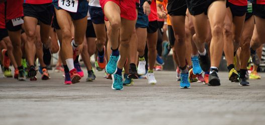 Foto delle gambe di maratoneti che corrono su strada.